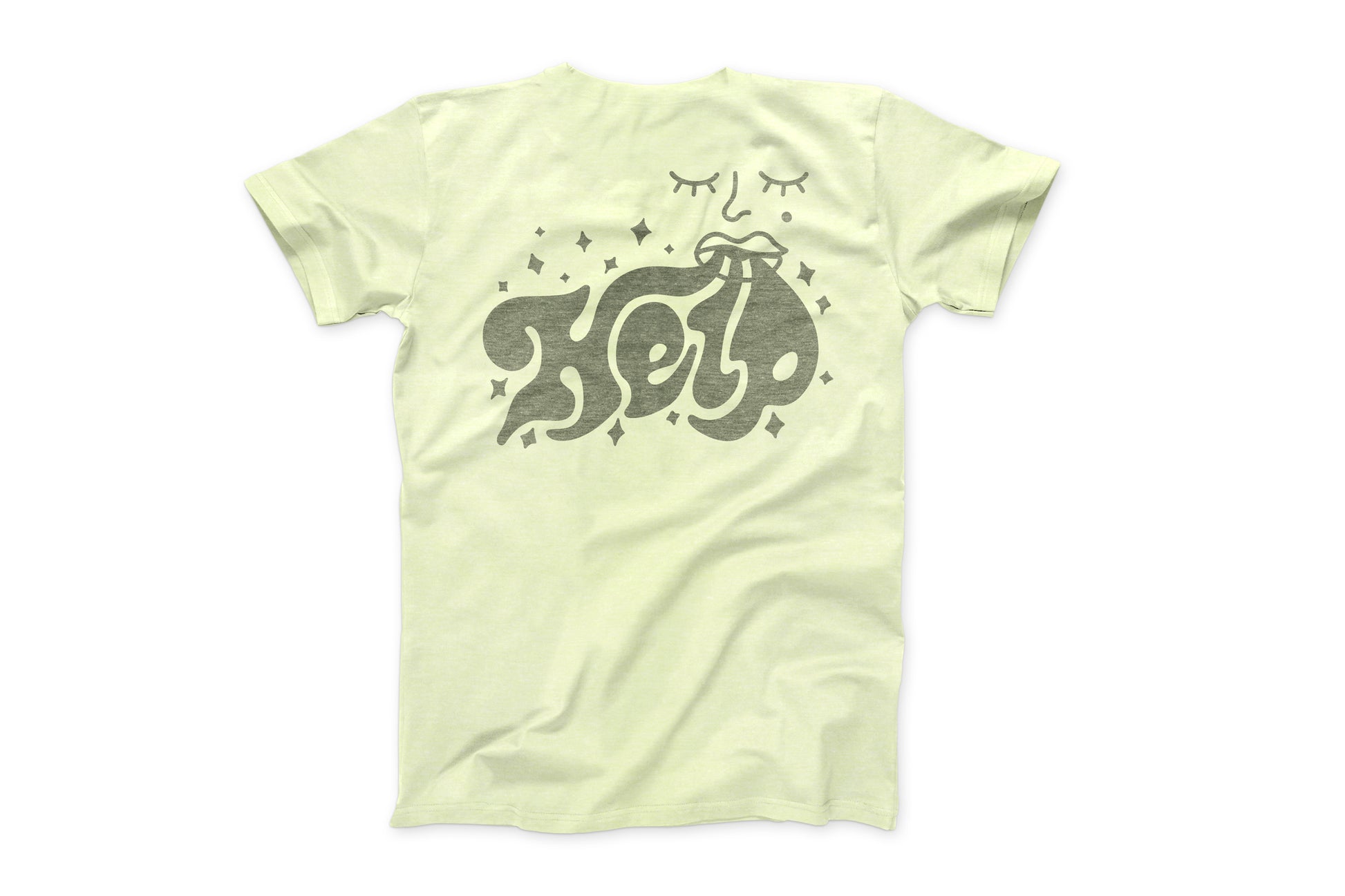 This is a photo of the back of the "Daily Tee". The shirt is a light pale green and has a large design on it. The design is of a mouth exhaling the word "HELP" which is in a art nouveau style. Small stars surround the design.